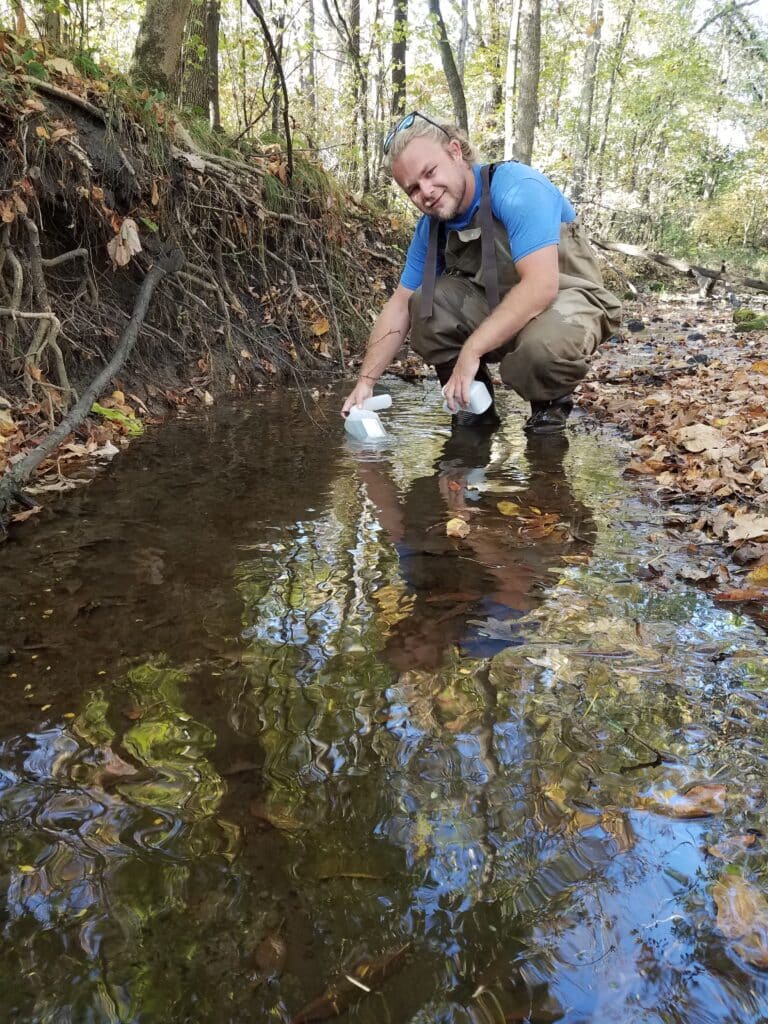 Dane McKittrick, Clean River Partners, collects water samples from Rice Creek.